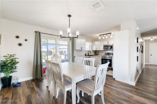 dining room with dark hardwood / wood-style floors, sink, a notable chandelier, and a textured ceiling