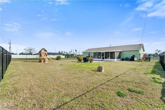 view of yard featuring a playground, a fenced backyard, and a sunroom