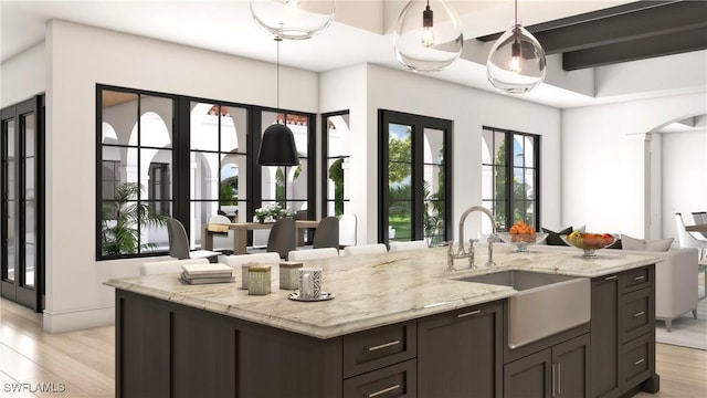 kitchen with pendant lighting, sink, dark brown cabinets, and light wood-type flooring