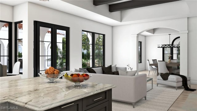 living room featuring an inviting chandelier, beamed ceiling, and light wood-type flooring