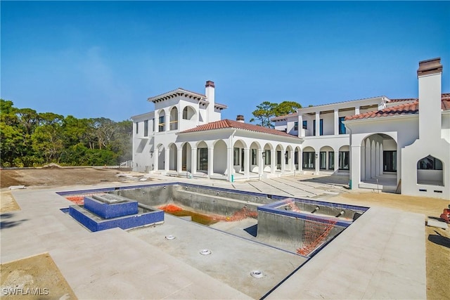 back of property with a patio and a pool with hot tub