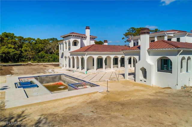 back of property with an in ground hot tub and a patio area