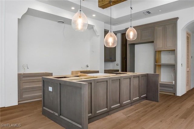 kitchen featuring decorative light fixtures, a kitchen island, and hardwood / wood-style flooring