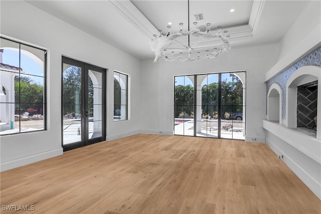 unfurnished dining area with hardwood / wood-style flooring, crown molding, a towering ceiling, and french doors