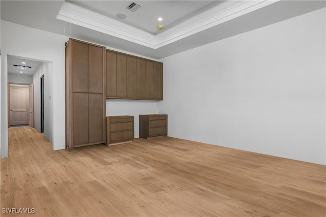 interior space featuring a tray ceiling, ornamental molding, and light wood-type flooring