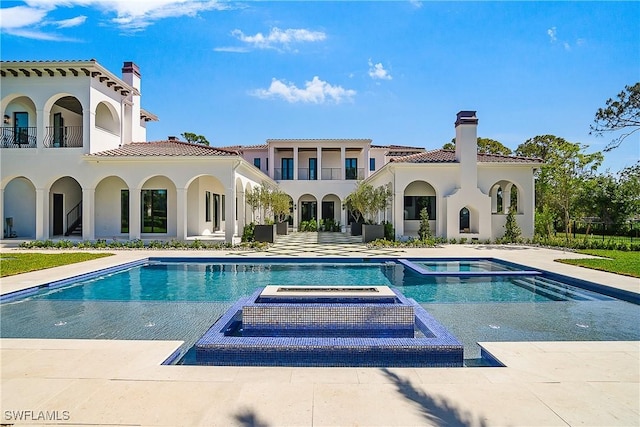 50 Mahogany Dr, Naples, FL 34108 - back of house with a chimney, stucco siding, a tiled roof, a pool with connected hot tub, and a patio area
