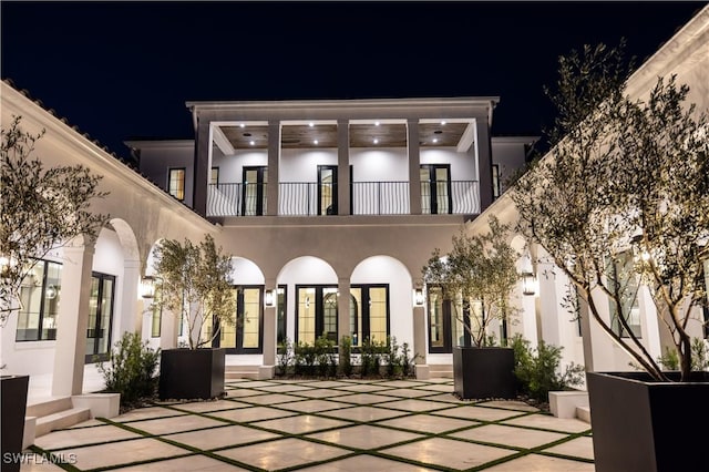 50 Mahogany Dr, Naples, FL 34108 - back of house at night with a patio area, stucco siding, french doors, and a balcony