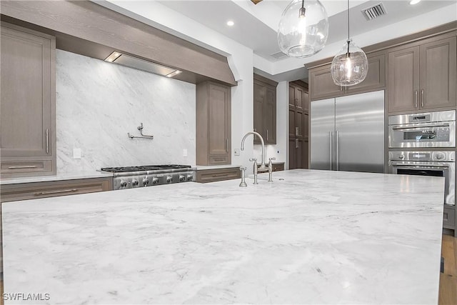 50 Mahogany Dr, Naples, FL 34108 - kitchen with visible vents, light stone counters, stainless steel appliances, and tasteful backsplash