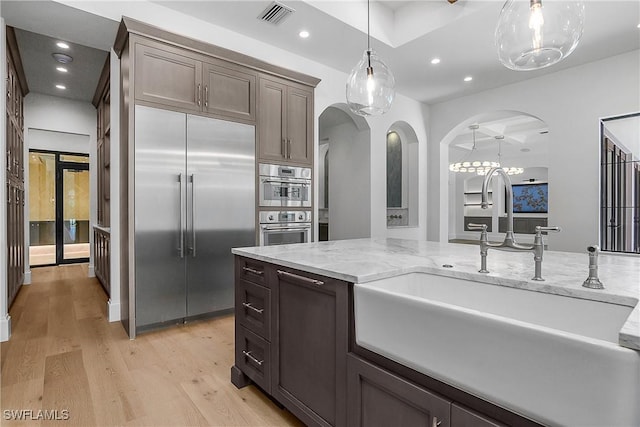 50 Mahogany Dr, Naples, FL 34108 - kitchen featuring arched walkways, appliances with stainless steel finishes, light wood finished floors, a sink, and visible vents