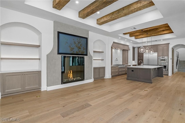 50 Mahogany Dr, Naples, FL 34108 - kitchen featuring light wood finished floors, stainless steel appliances, built in features, a glass covered fireplace, and open floor plan