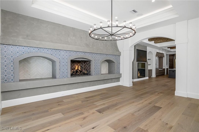 50 Mahogany Dr, Naples, FL 34108 - unfurnished dining area with wood finished floors, arched walkways, a warm lit fireplace, visible vents, and a raised ceiling