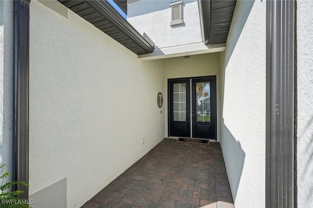 view of exterior entry with french doors and stucco siding