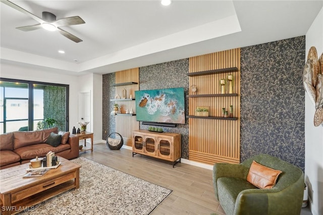 living area featuring wallpapered walls, an accent wall, and a raised ceiling