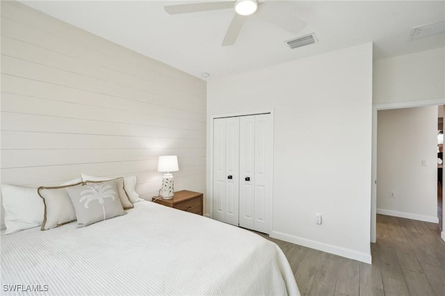 bedroom with a closet, visible vents, ceiling fan, wood finished floors, and baseboards