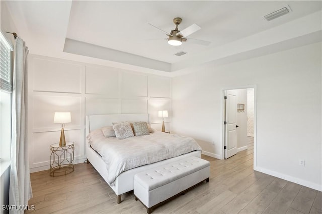 bedroom with light wood finished floors, visible vents, and a decorative wall