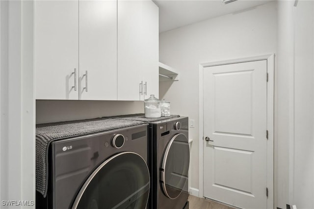 washroom with cabinet space, separate washer and dryer, and wood finished floors