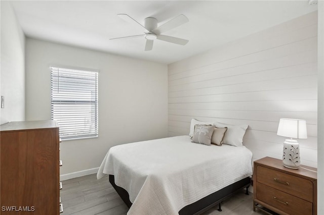 bedroom with ceiling fan, light wood finished floors, and baseboards