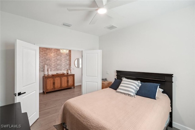 bedroom with a ceiling fan, baseboards, visible vents, and wood finished floors