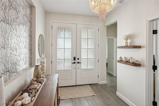 doorway featuring baseboards, a chandelier, wood finished floors, and french doors