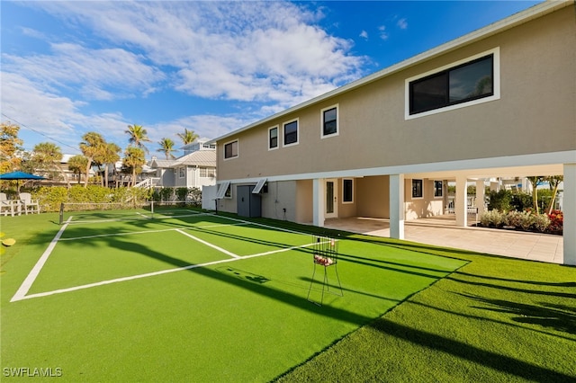 view of tennis court with a patio