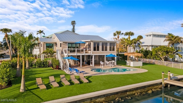 back of property with a water view, a yard, a fenced in pool, and a patio area