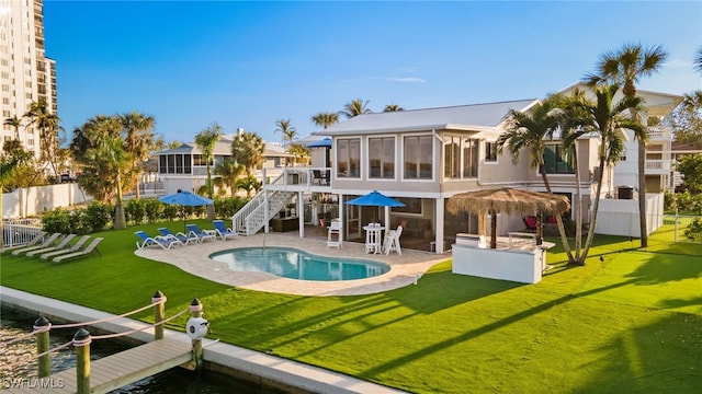 rear view of house with a fenced in pool, a patio, a sunroom, and a yard