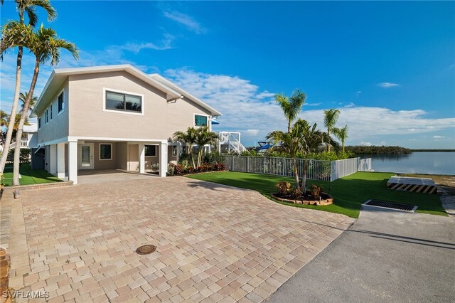 back of house featuring a lawn and a water view