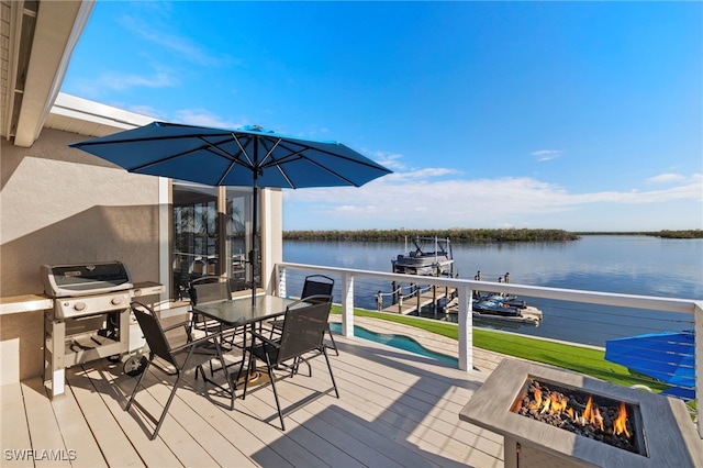 wooden deck featuring a water view, a grill, a fire pit, and a boat dock