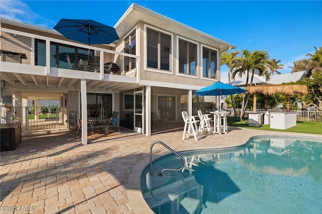 rear view of house with outdoor dining space, a balcony, a fenced in pool, and a patio area