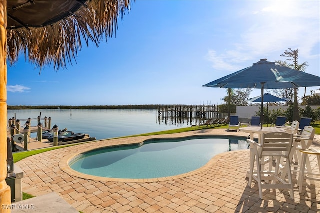 view of pool with a water view, a patio area, and a boat dock