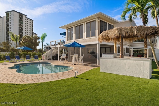 back of house with an outdoor pool, a patio area, stucco siding, a lawn, and stairway