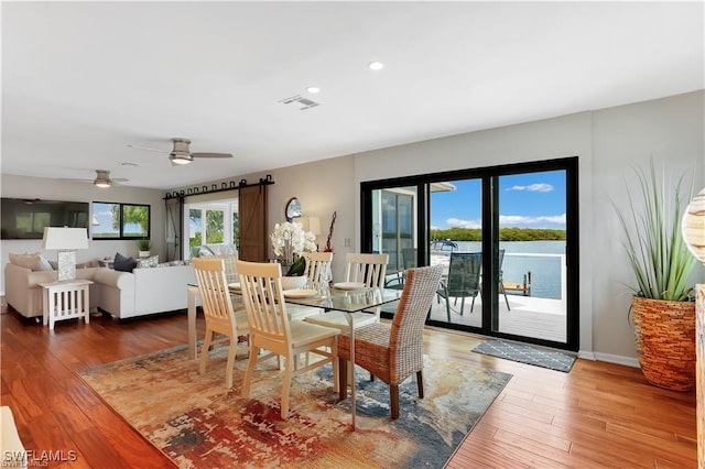 dining room with hardwood / wood-style floors, ceiling fan, and a water view