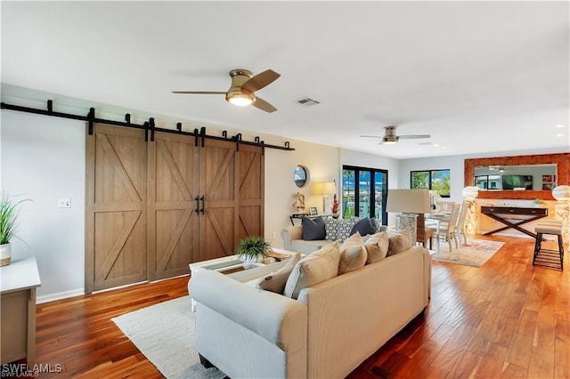 living room with hardwood / wood-style flooring, ceiling fan, and a barn door