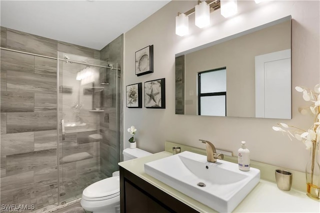 bathroom featuring vanity, an enclosed shower, and toilet