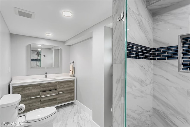 bathroom with tiled shower, vanity, and toilet