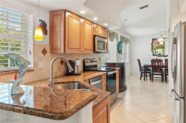 kitchen featuring dark stone countertops, sink, kitchen peninsula, and appliances with stainless steel finishes