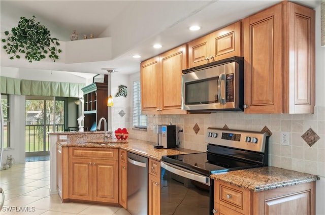 kitchen with appliances with stainless steel finishes, light stone countertops, sink, and backsplash