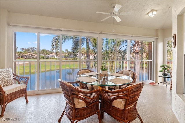 sunroom / solarium featuring a water view and ceiling fan