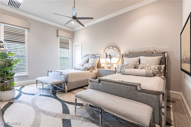 bedroom featuring light wood-type flooring, ornamental molding, and ceiling fan