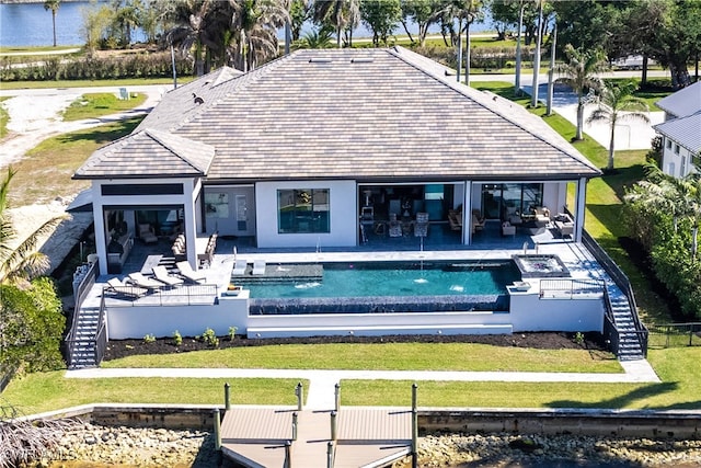 rear view of property featuring a swimming pool with hot tub, pool water feature, and a patio