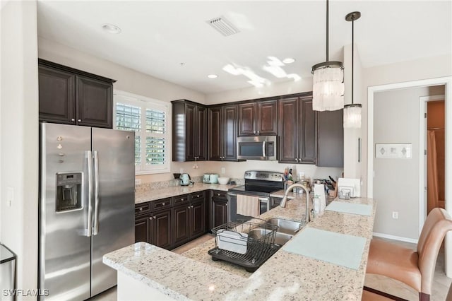 kitchen with a kitchen bar, decorative light fixtures, dark brown cabinets, and appliances with stainless steel finishes