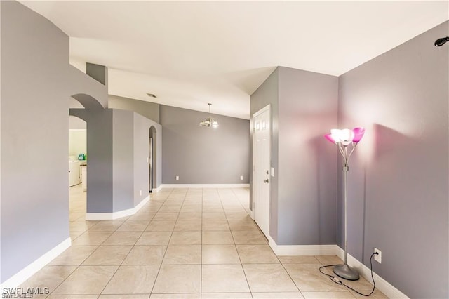 corridor with vaulted ceiling, light tile patterned floors, and a notable chandelier