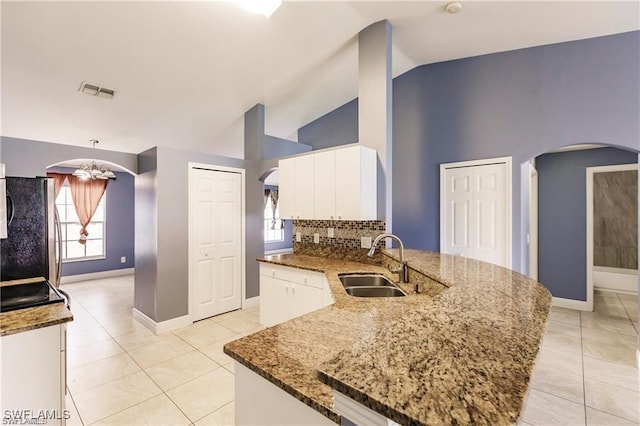 kitchen with stone countertops, a kitchen island, sink, and stainless steel fridge