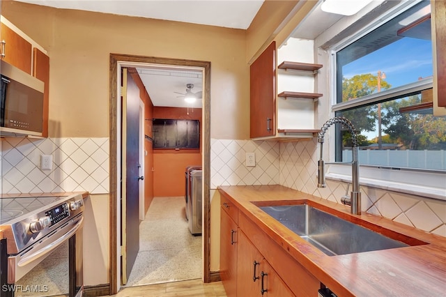 kitchen with butcher block counters, sink, decorative backsplash, and stainless steel appliances