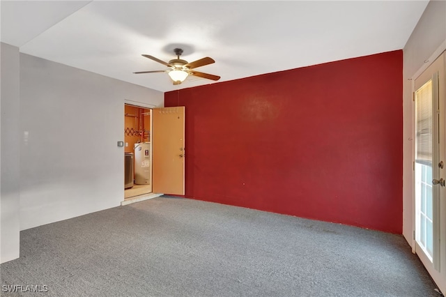 spare room with water heater, carpet, and ceiling fan