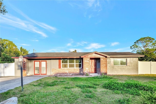 ranch-style home with french doors and a front lawn