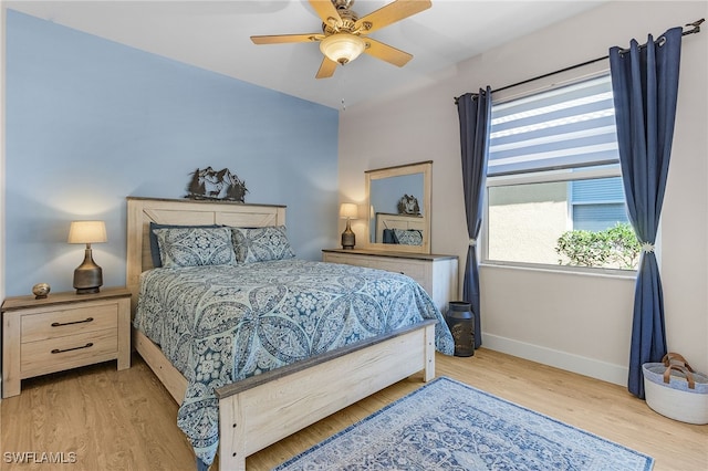 bedroom with baseboards, a ceiling fan, and light wood-style floors