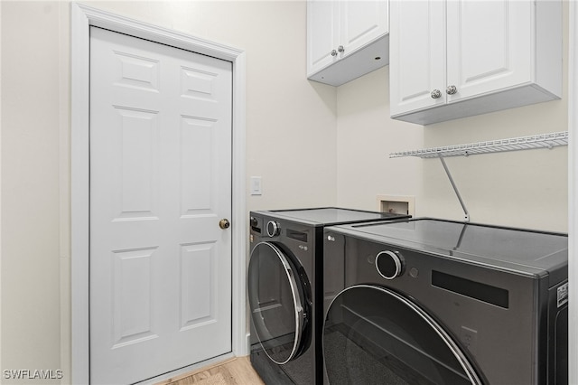 washroom featuring light wood-type flooring, cabinet space, and separate washer and dryer