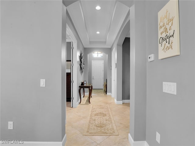 hall featuring arched walkways, crown molding, recessed lighting, a raised ceiling, and baseboards