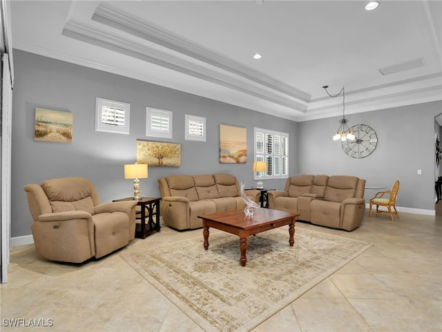 living room featuring ornamental molding, a tray ceiling, a notable chandelier, and baseboards